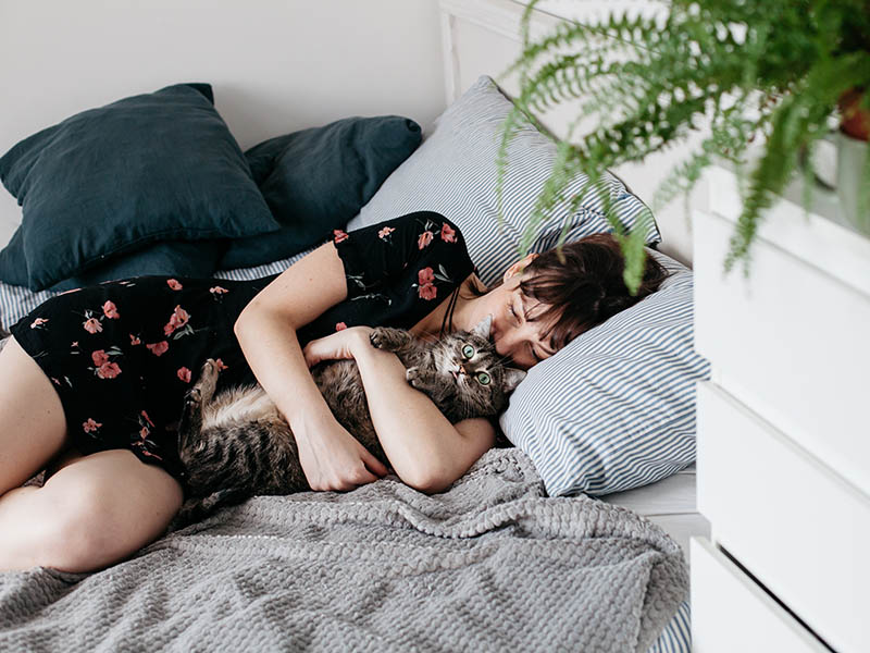 женщина обнимает кошку в постели